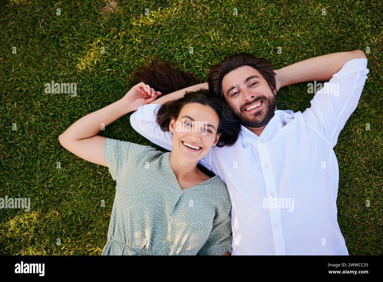 Felice coppia giovane sdraiato sull'erba Foto Stock