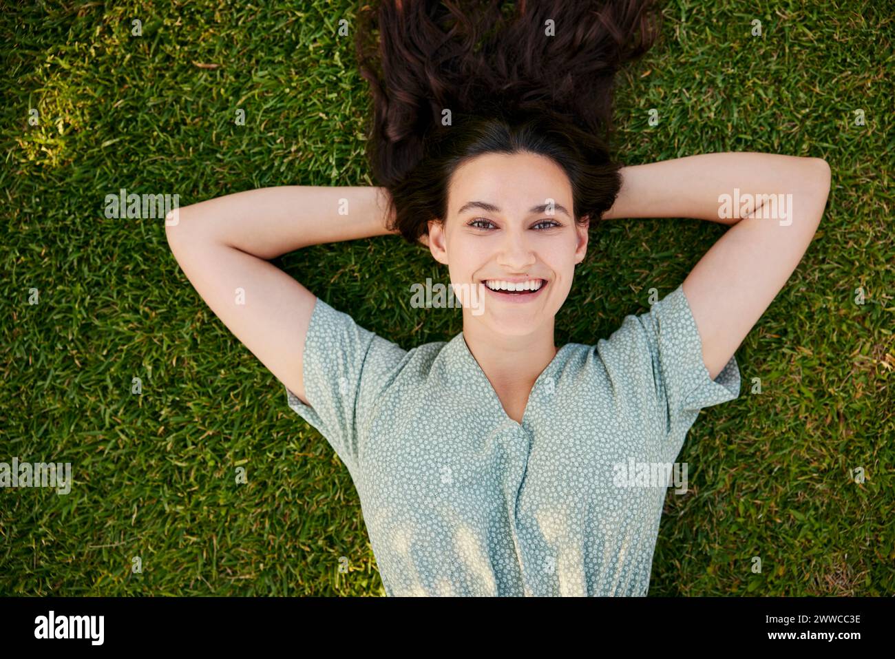 Bella donna sorridente stesa sull'erba Foto Stock