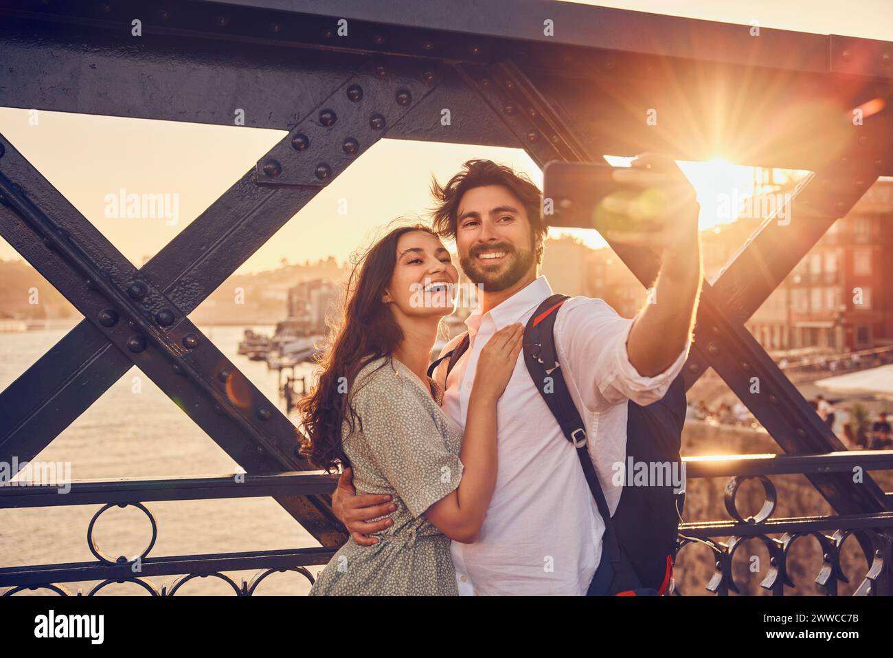 Coppia sorridente che fa selfie tramite smartphone al ponte Dom Luis di Porto, Portogallo Foto Stock