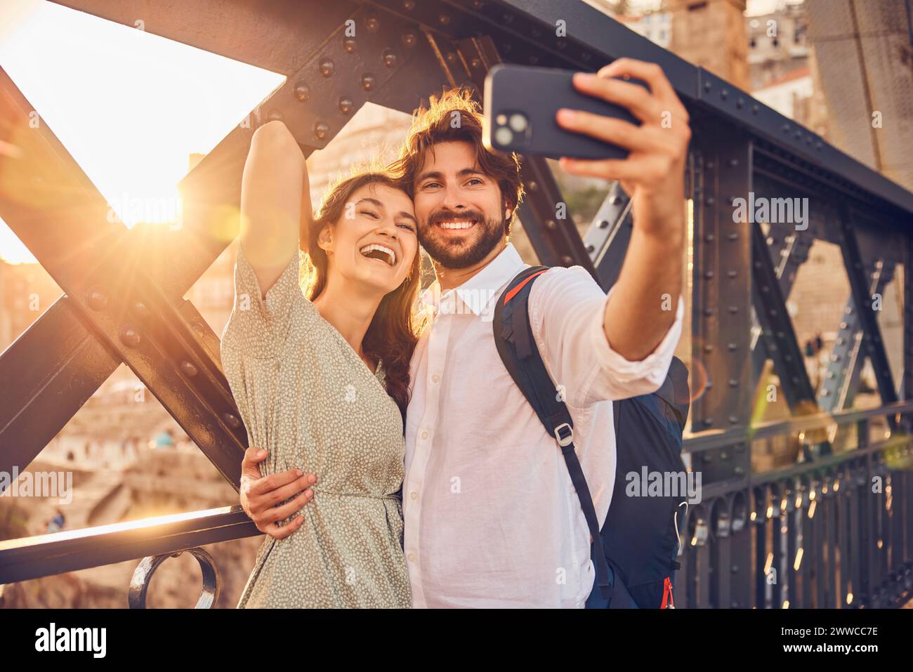 Una coppia allegra che scatta selfie tramite smartphone al ponte Dom Luis di Porto, Portogallo Foto Stock