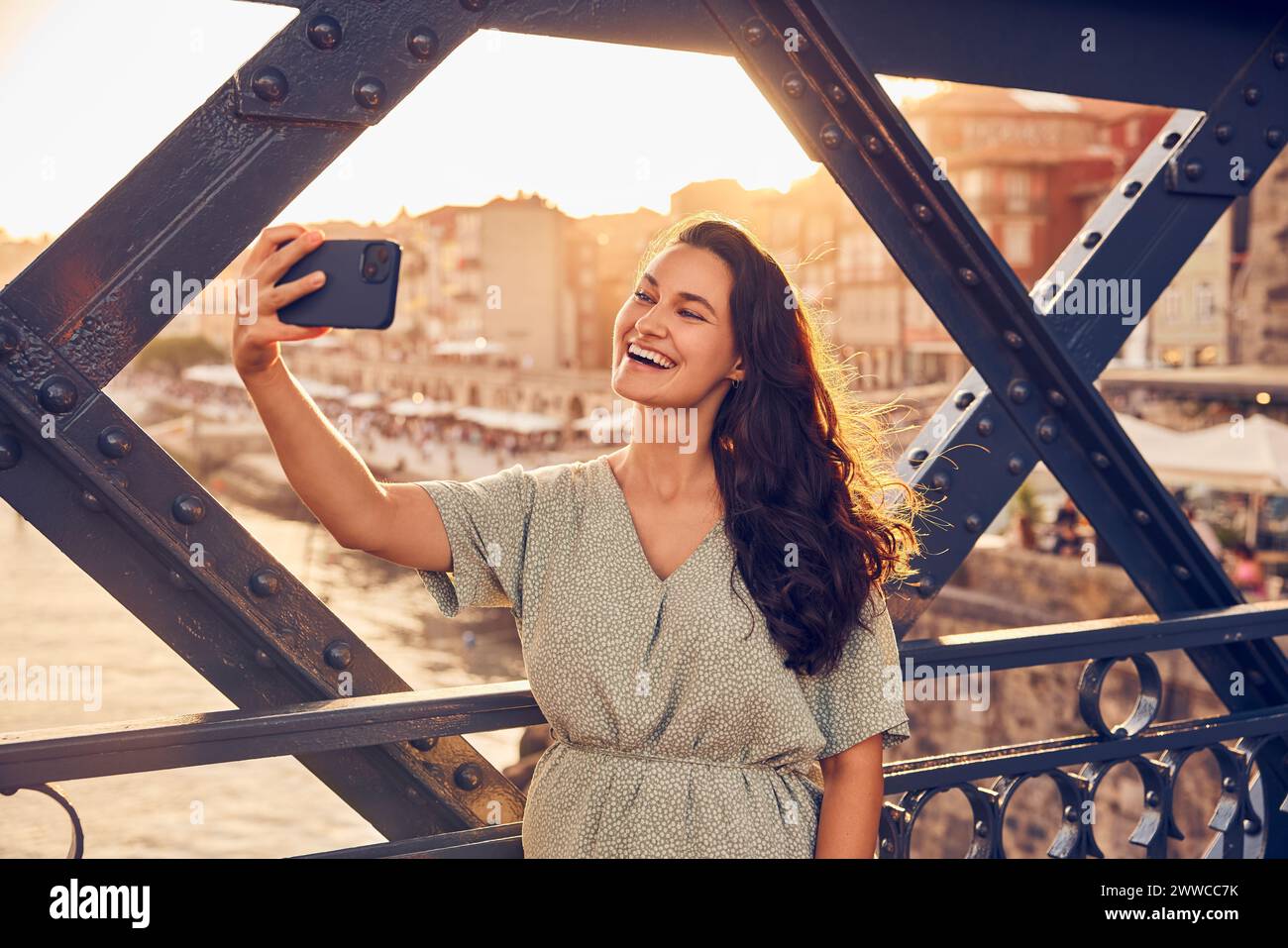 Giovane donna felice che si sta facendo selfie con il cellulare al ponte Dom Luis, Porto, Portogallo Foto Stock