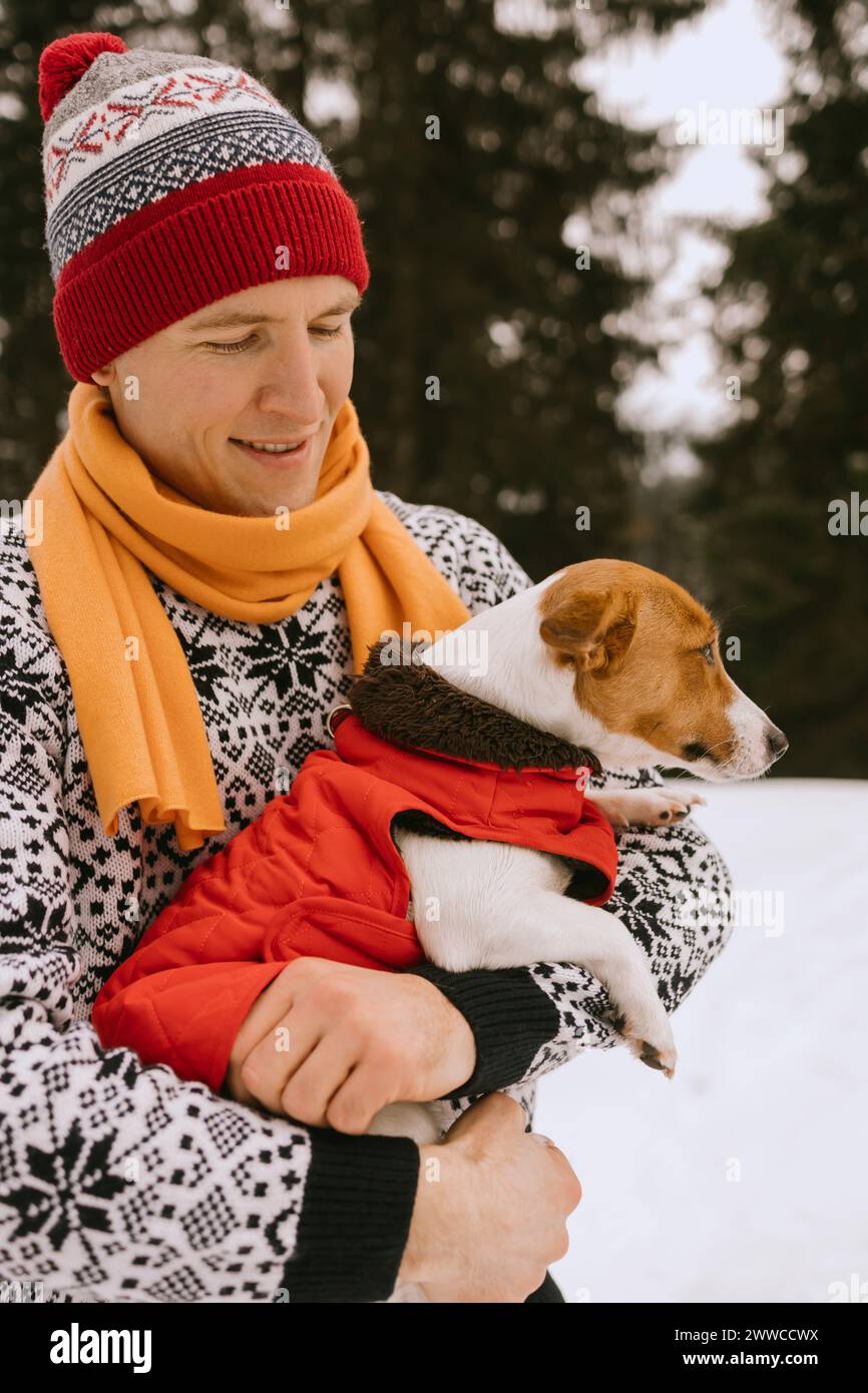 Uomo e cane che indossano abiti caldi nella foresta invernale Foto Stock