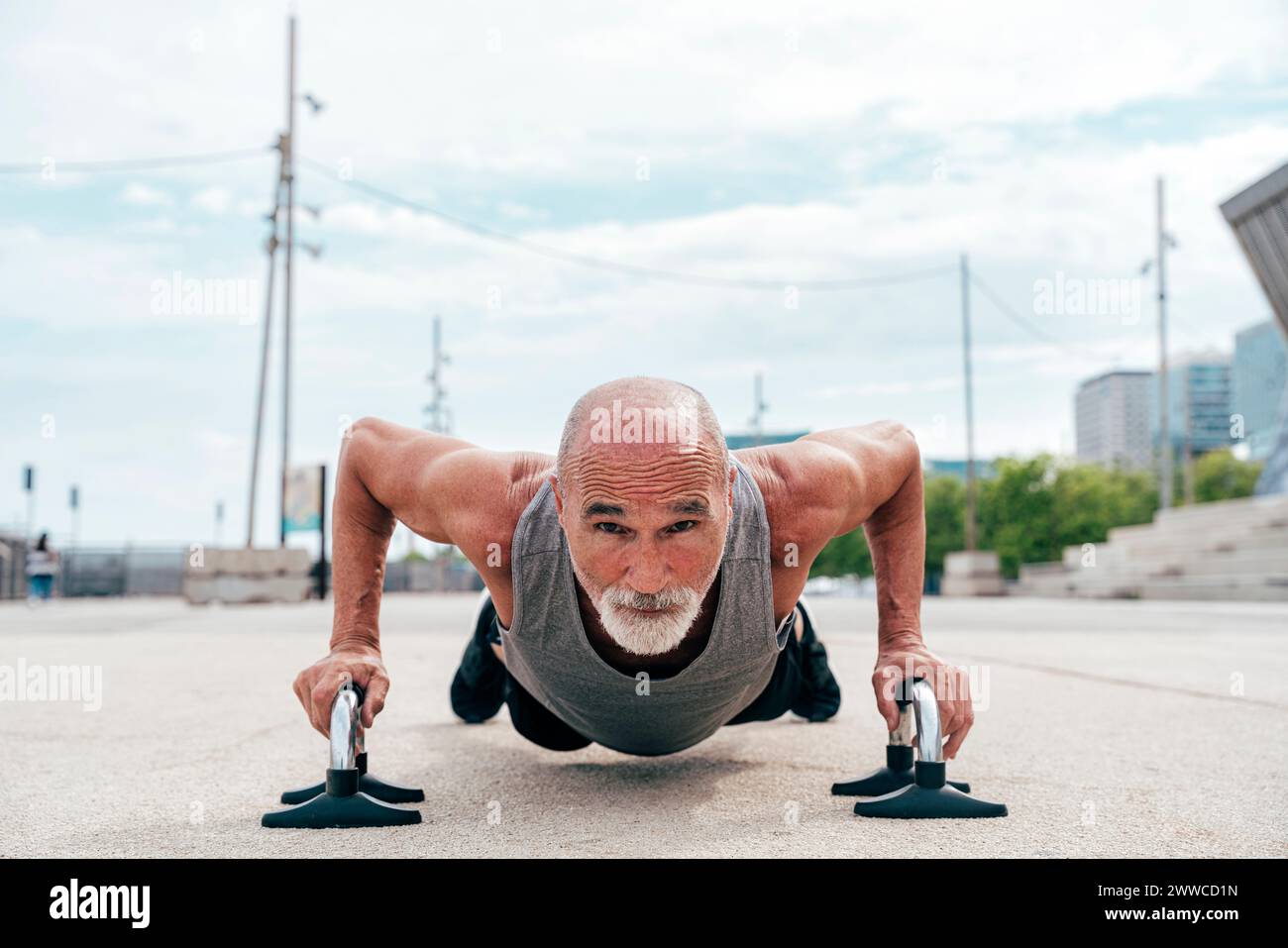 Uomo anziano attivo che fa push-up sulle maniglie Foto Stock