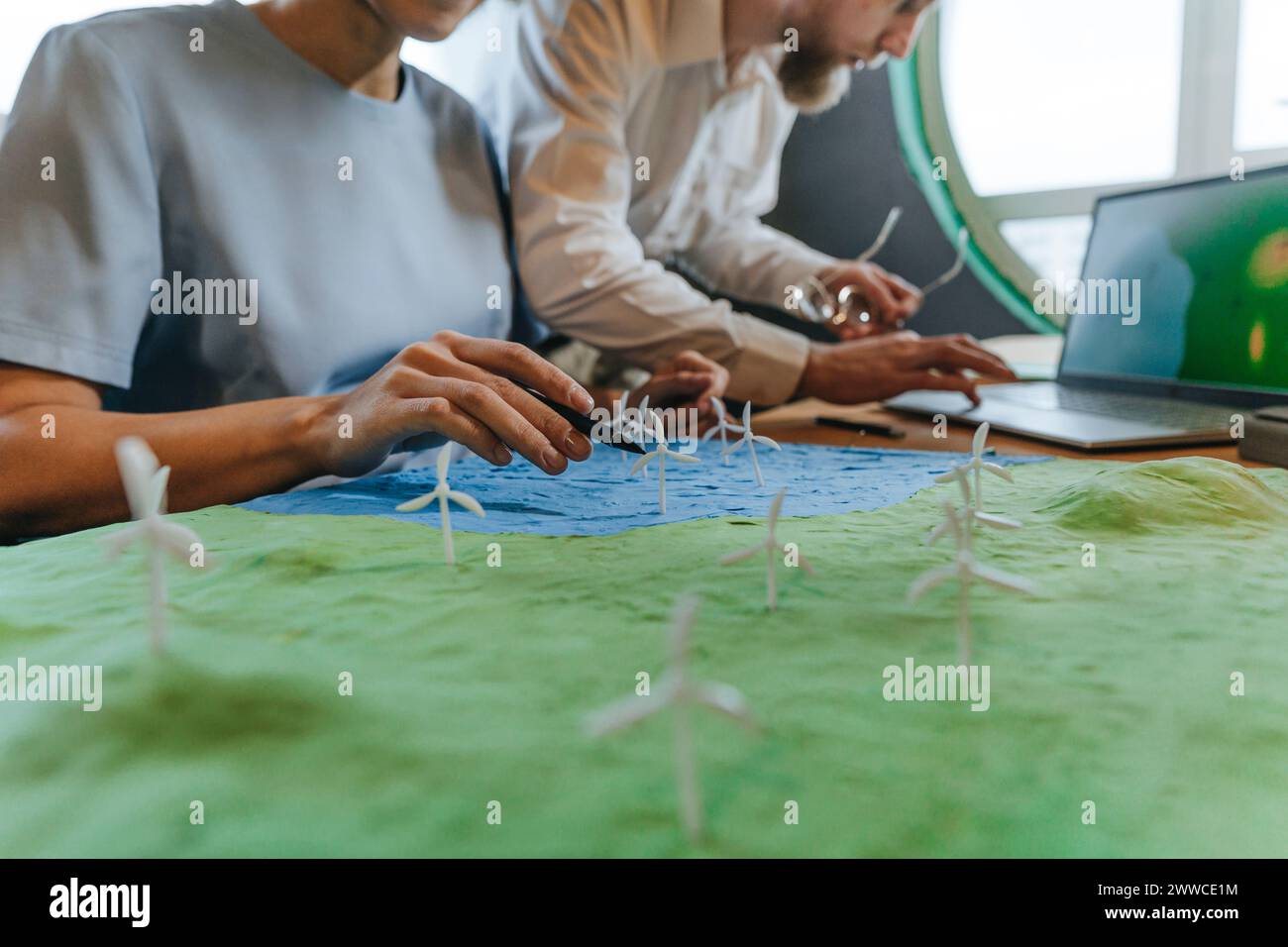 Colleghi con modello eolico e laptop in ufficio Foto Stock Colleghi con modello eolico e laptop in ufficio Foto Stock