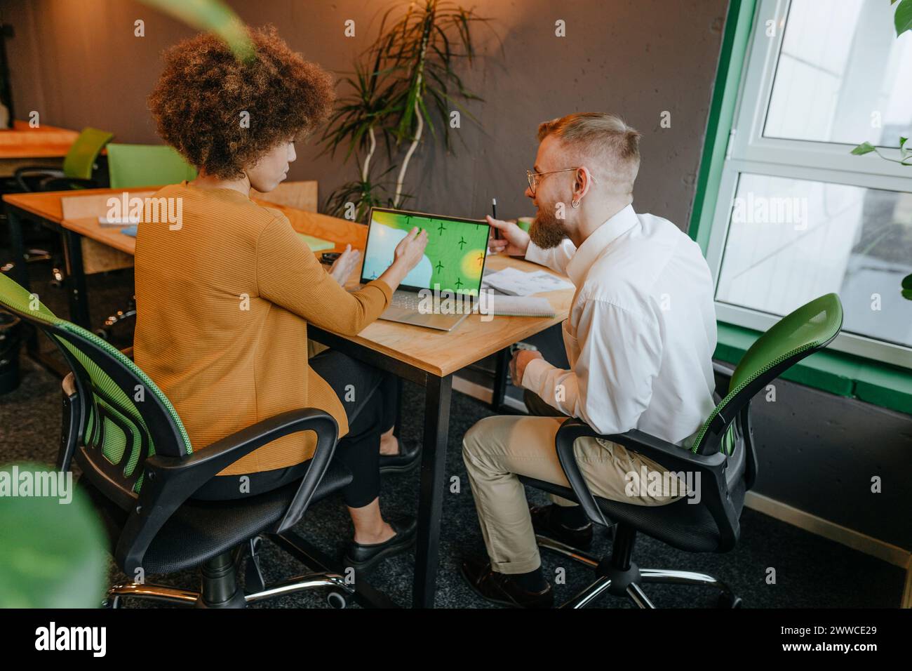 Colleghi di lavoro multirazziali che discutono con un laptop seduto alla scrivania in un ufficio di coworking Foto Stock