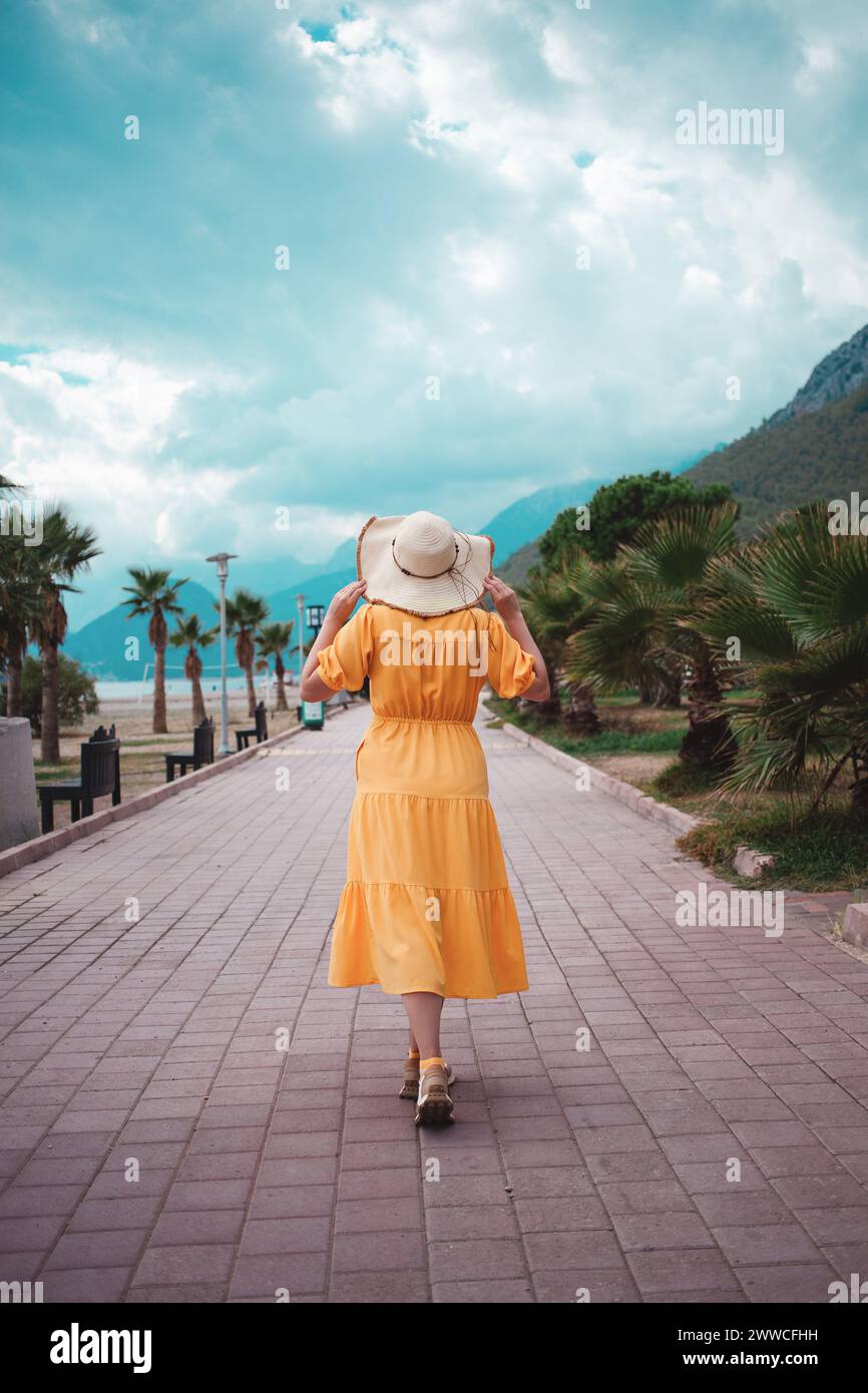 Donna in abito giallo, vagabondante tra le montagne, esplorando la bellezza del viaggio. Foto Stock