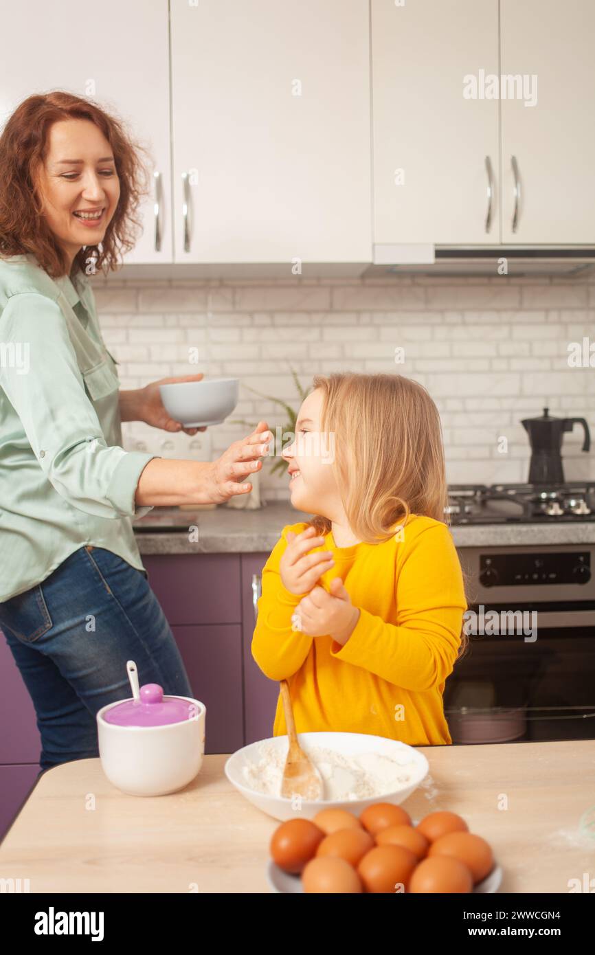 nonna e nipote stanno facendo la torta in cucina, la famiglia felice, donna e bambino sorridono. Divertirsi Foto Stock