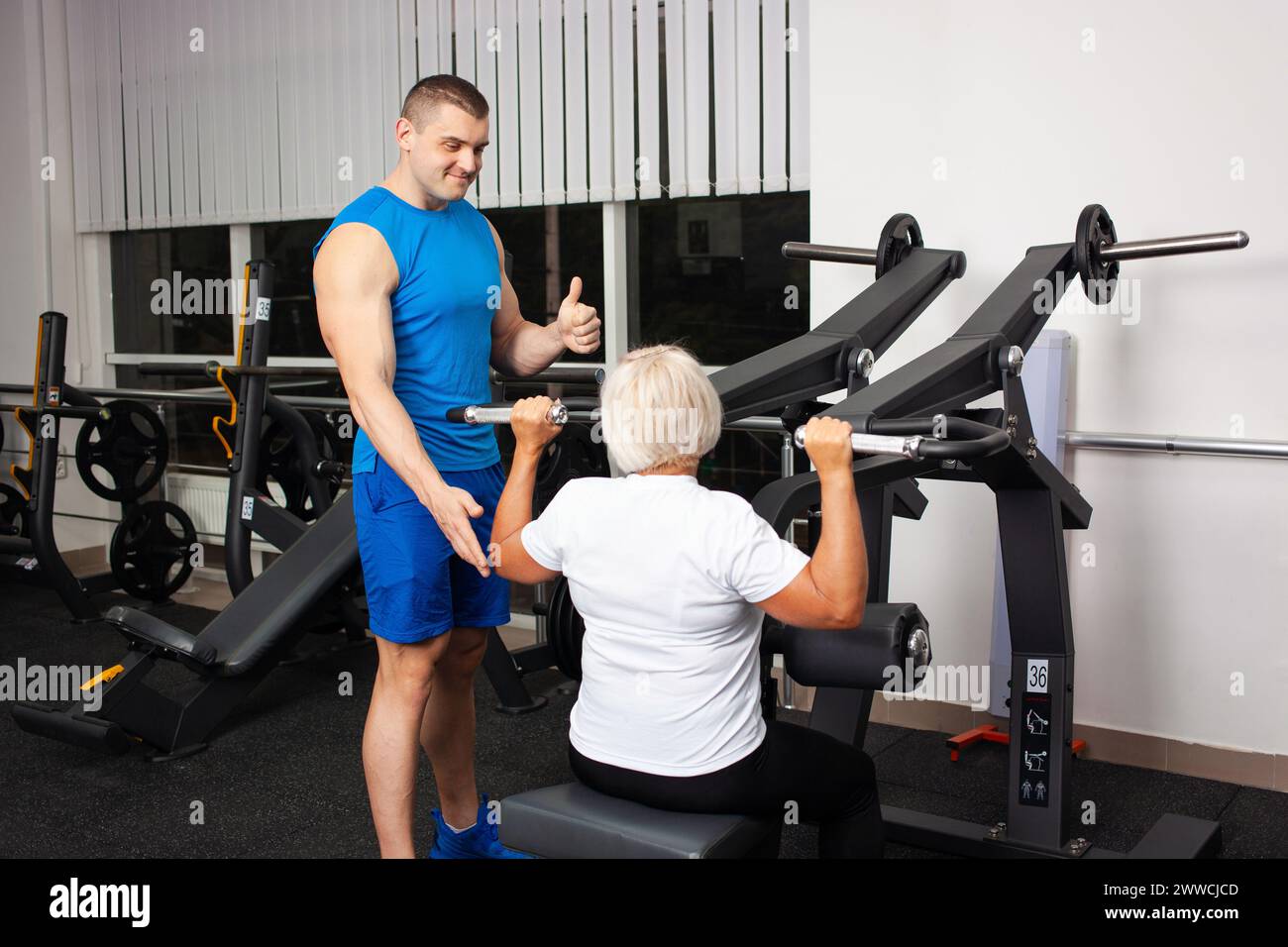 Centro di riabilitazione palestra, recupero da lesioni e fratture. L'istruttore mostra a una donna anziana come eseguire un esercizio sul simulatore. Healt Foto Stock