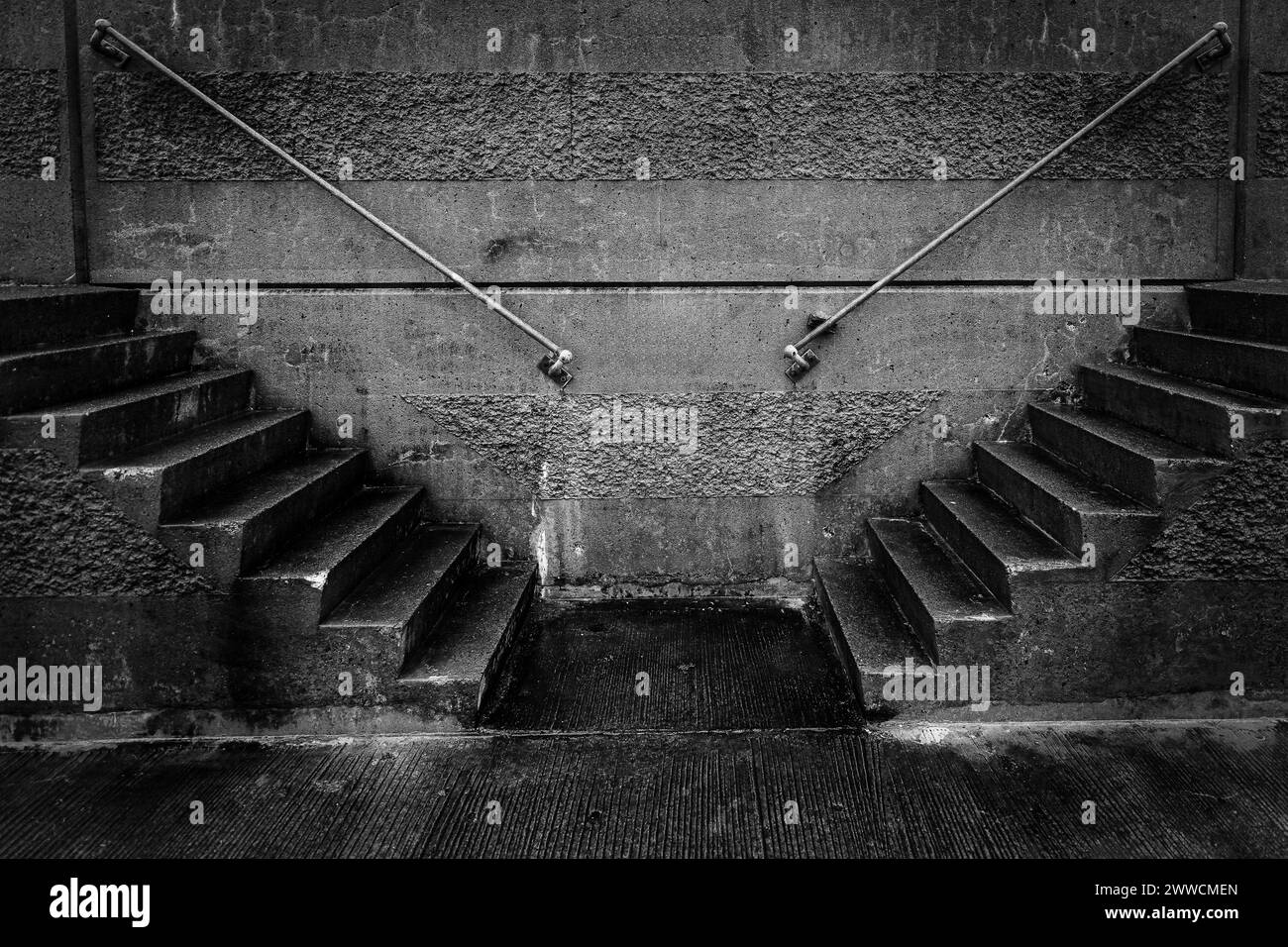 Due serie di scale sono mostrate in una foto in bianco e nero. Le scale sono fatte di cemento e si trovano in un edificio. La foto ha un mucchio e un mucchio Foto Stock
