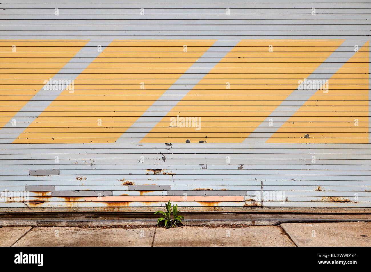 Vista orizzontale della porta del garage grigia chiusa con strisce diagonali gialle Foto Stock
