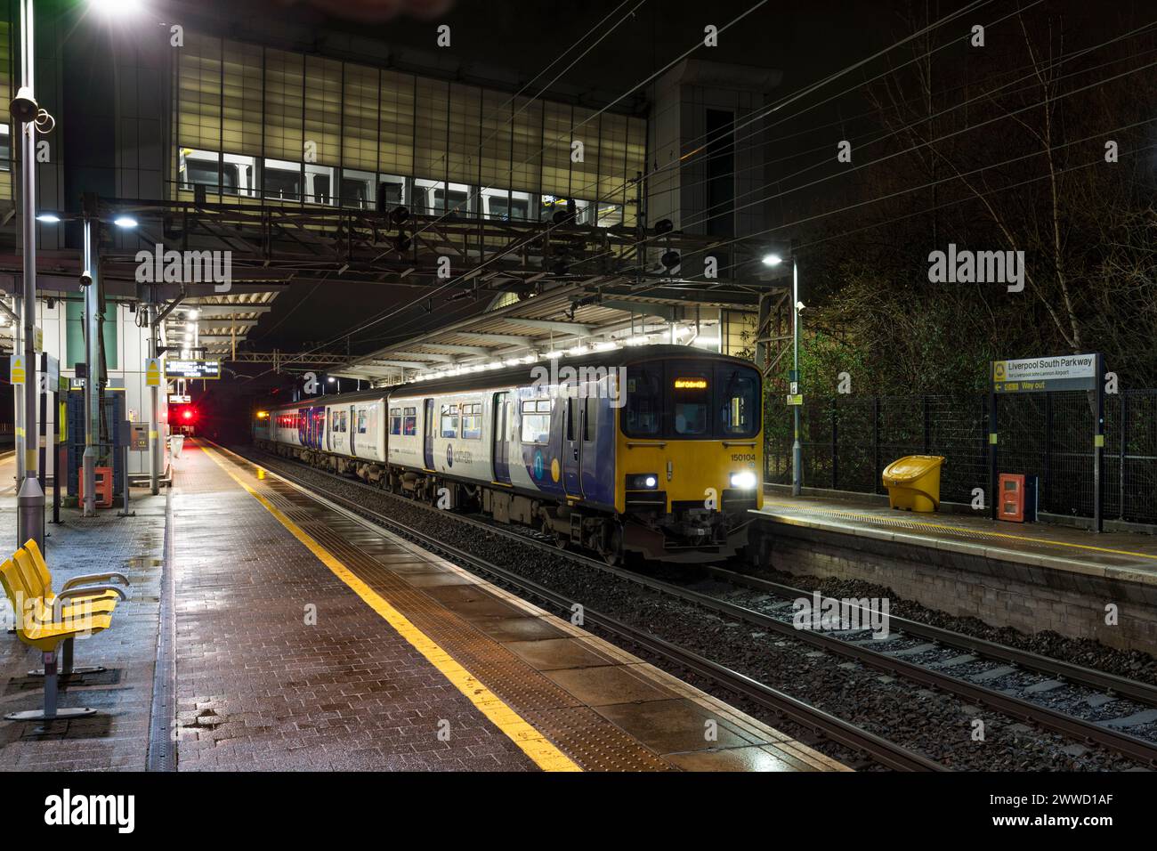 2 treni diesel a più unità di classe 150 Northern Rail che fanno scalo alla stazione ferroviaria di Liverpool South Parkway di notte Foto Stock