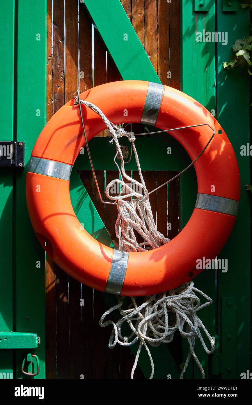 Giubbotto arancione sulla recinzione di legno verde Foto Stock