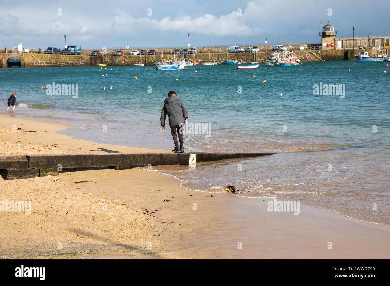 St Ives, Cornovaglia, 23 marzo 2024, le persone erano fuori a godersi il sole primaverile tra le docce a St Ives, Cornovaglia. La temperatura era fredda di 9C ma con forti venti sembrava molto più fredda. Le previsioni sono per nuvole leggere e brezza moderata per il futuro. Crediti: Keith Larby/Alamy Live News Foto Stock