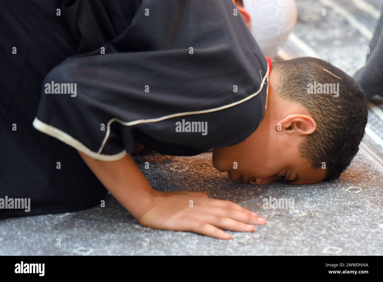 Un ragazzo musulmano prega in posizione inginocchiata toccando il naso a terra (Sujud) durante la quinta preghiera del giorno (Isha) durante il Ramadan nella moschea islamica di Vendrell. La comunità musulmana di El Vendrell celebra il Ramadan e il loro raduno nella Moschea Islamica della città per eseguire la preghiera notturna chiamata "Isha". A Vendrell ci sono circa 2.600 persone registrate di diverse nazionalità e la loro religione è l'Islam, a parte i figli e le figlie di questi immigrati già nati in Spagna, dove ci sono circa 3.000 musulmani in una città di circa 39.000 abitanti. Prima di pregare, Foto Stock