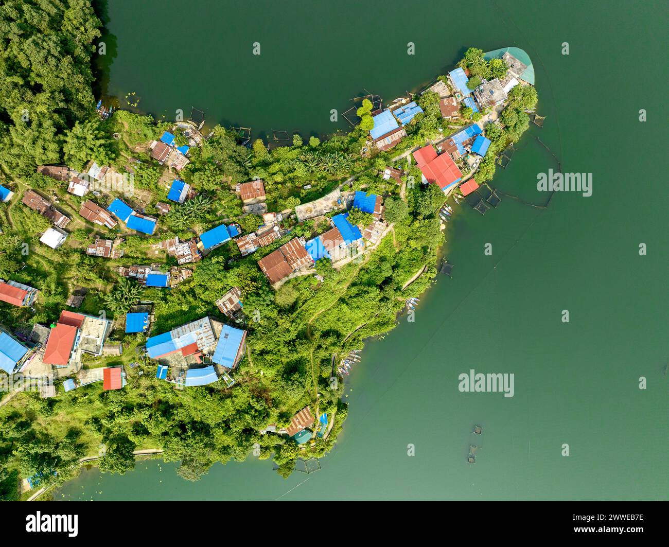 Vista aerea del lago Begnas, il terzo lago più grande del Nepal. Natura selvaggia e alberi con case circondano il lago, tipiche barche nepalesi in acqua Foto Stock