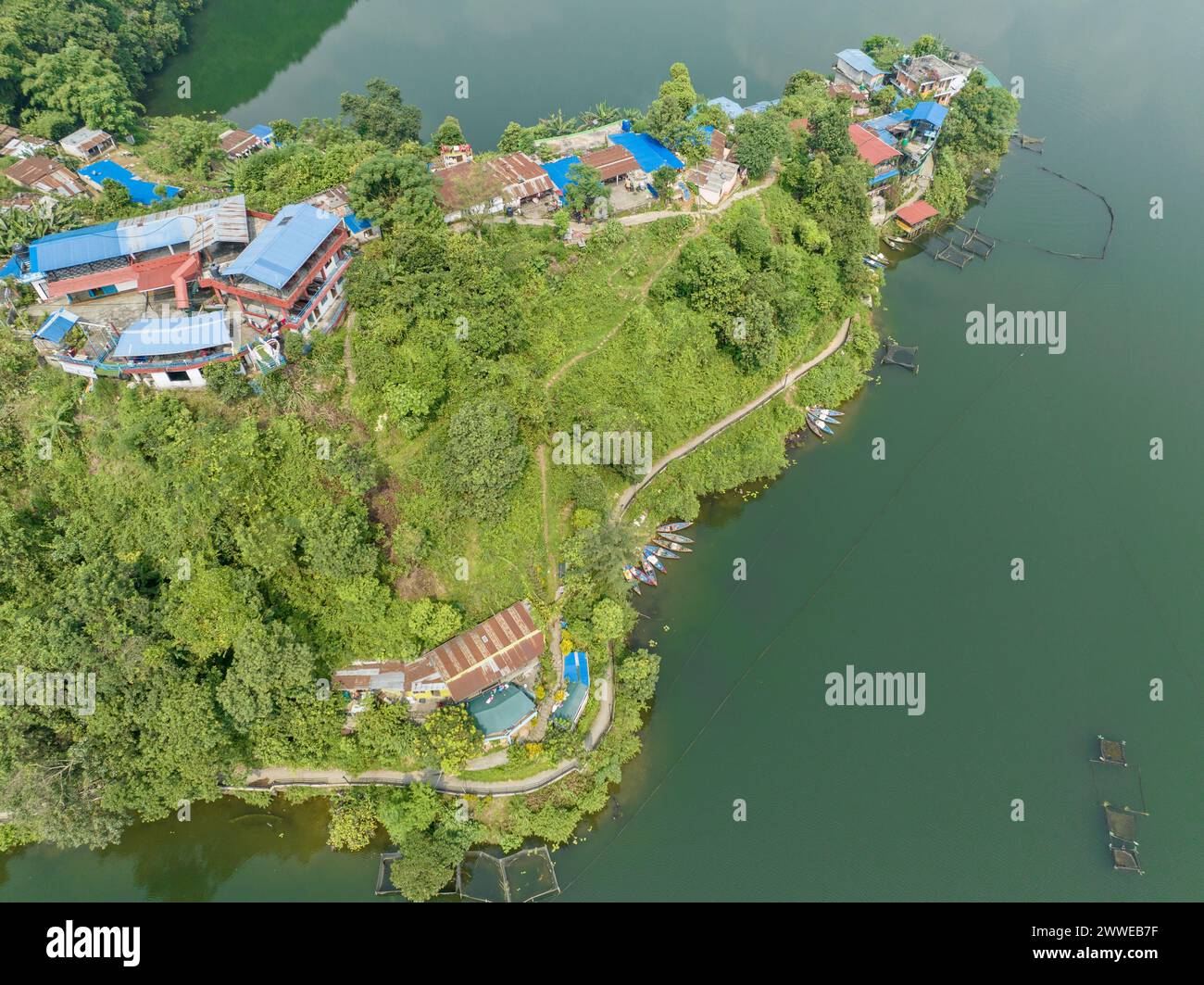 Vista aerea del lago Begnas, il terzo lago più grande del Nepal. Natura selvaggia e alberi con case circondano il lago, tipiche barche nepalesi in acqua Foto Stock