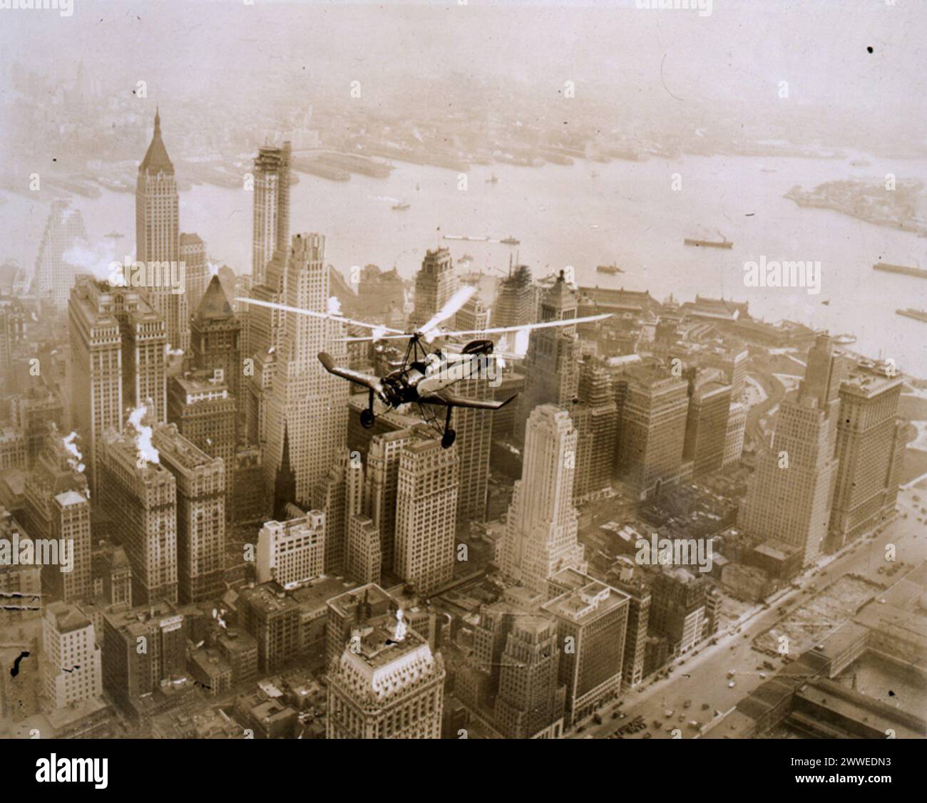 Fotografia c.1931 che mostra un Cierva Autogiro di fabbricazione britannica che sorvola l'isola di Manhattan, sviluppata dall'ingegnere spagnolo Juan de la Cierva negli anni '1920, che illustra i primi velivoli a rotazione e l'innovazione dell'aviazione. Foto Stock