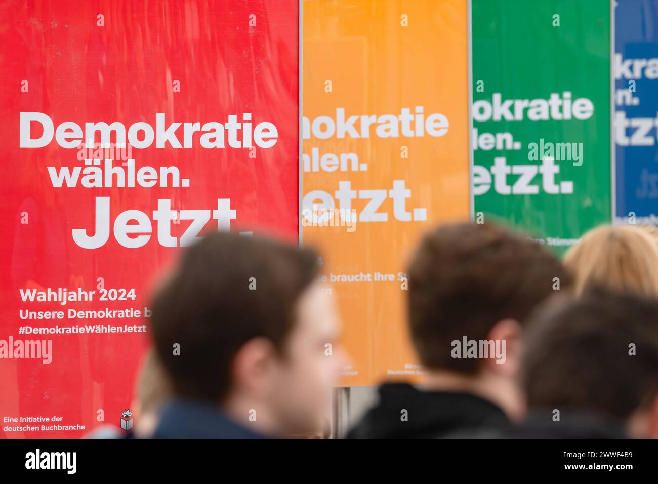 Besucher laufen vor Plakaten mit der Aufschrift Demokratie waehlen am 22.03.2024 in der Glashalle der Leipziger Messe. Gemeinsam mit dem Boersenverein des Deutschen Buchhandels Hat die Leipziger Bucmesse die Initiative DemokratieWaehlenJetzt gestartet. Mehr als 2000 Ausstellerinnen und Aussteller aus 40 Laendern nehmen teil. Auf dem Messegelaende sind parallel die Manga-Comic-con Seit 10 Jahren und die Antiquariatsmesse seit 30 Jahren dabei. Nach der Frankfurter Buchmesse ist die Leipziger Buchmesse derzeit die zweitgroesste Deutschlands. I visitatori camminano di fronte ai poster con l'iscrizione Foto Stock