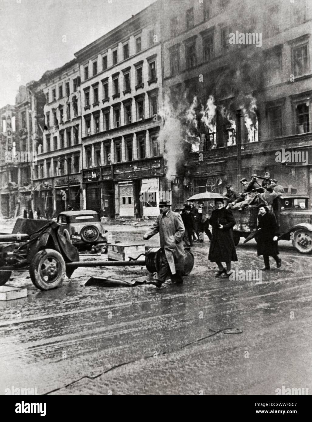 Berlino, Germania, 2 maggio 1945 fiamme scoppiarono da un edificio sullo sfondo mentre i soldati sovietici attraversavano Berlino sulla strada adiacente a Piazza Molen-Markt. Foto Stock