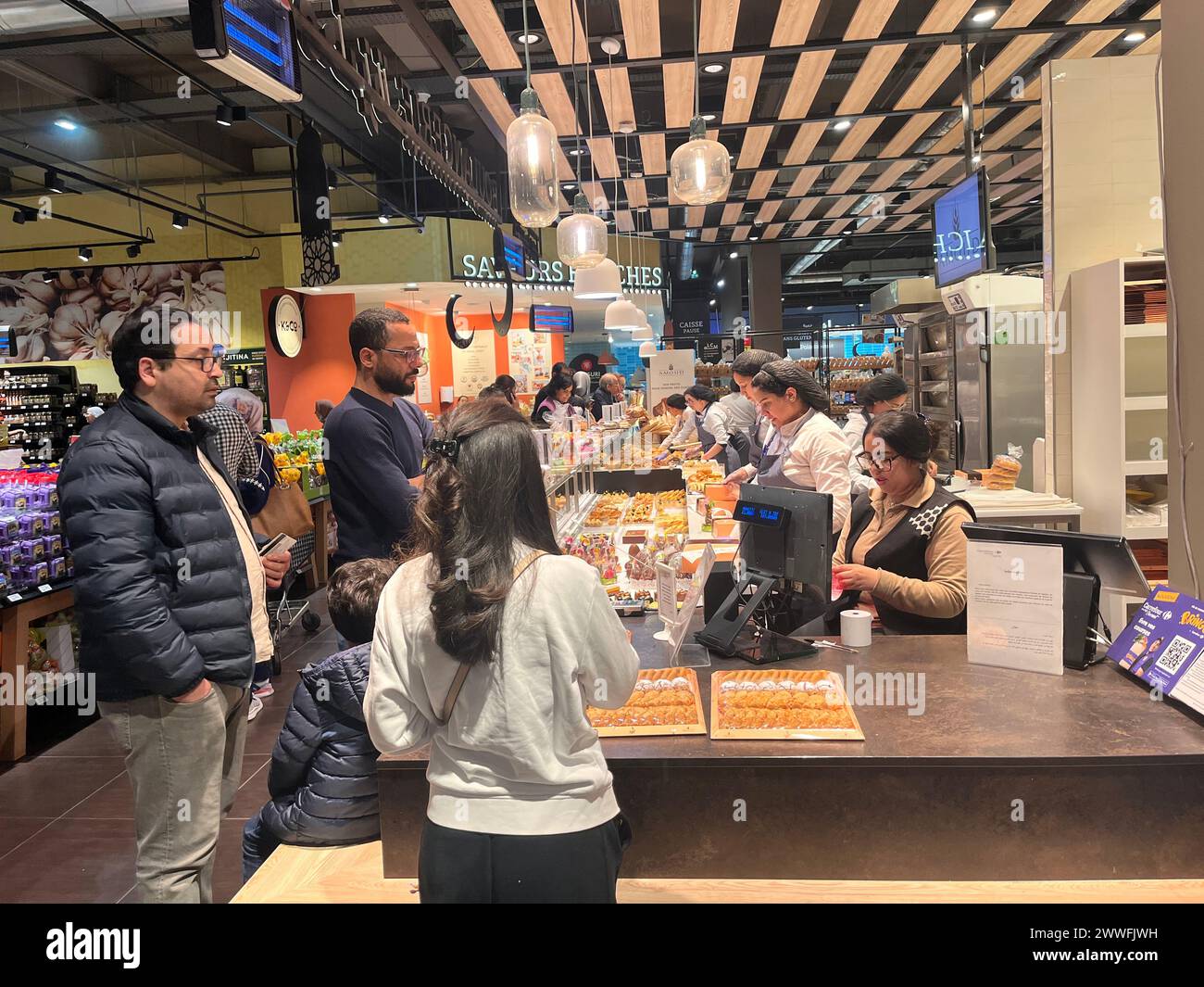 Rabat, Marocco. 23 marzo 2024. Questa foto scattata con un telefono cellulare mostra le persone in attesa di acquistare il dessert durante il Ramadan in un negozio di panetteria a Rabat, Marocco, 23 marzo 2024. Crediti: Huo Jing/Xinhua/Alamy Live News Foto Stock