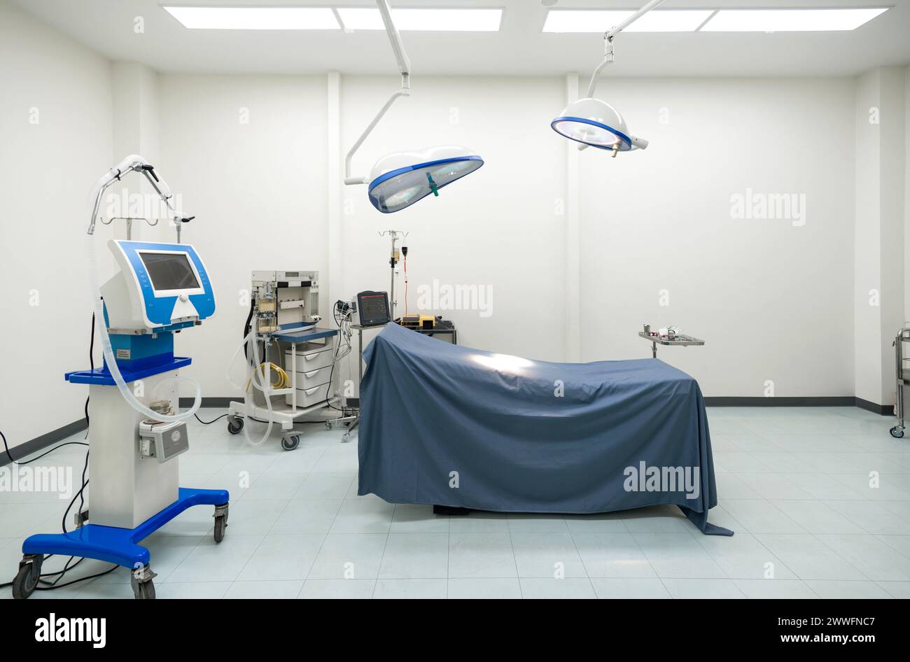 Una tipica sala operatoria in un ospedale con una lampada chirurgica sopra la testa per fornire un'illuminazione luminosa e direzionale all'équipe chirurgica durante la procedura. Foto Stock