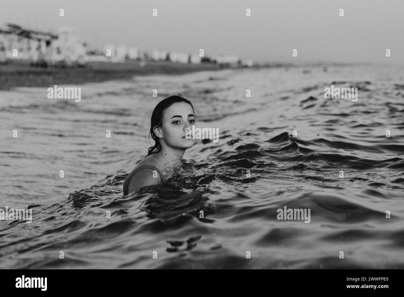 Giovane donna che nuota nelle calme acque dell'oceano a Dusk. Foto Stock
