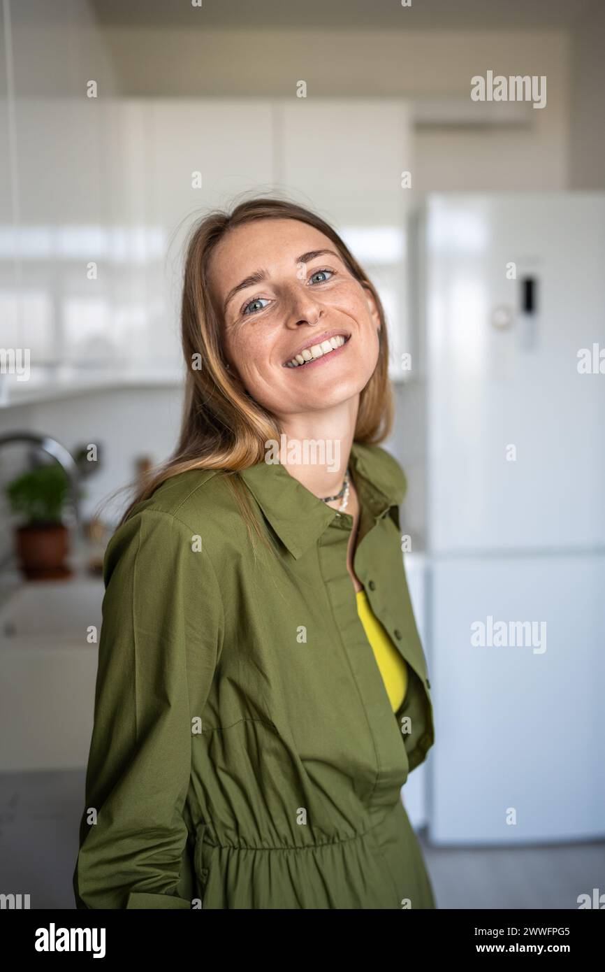 Ritratto donna bionda sorridente che guarda la fotocamera in piedi a casa con buon umore goditi il tempo. Foto Stock