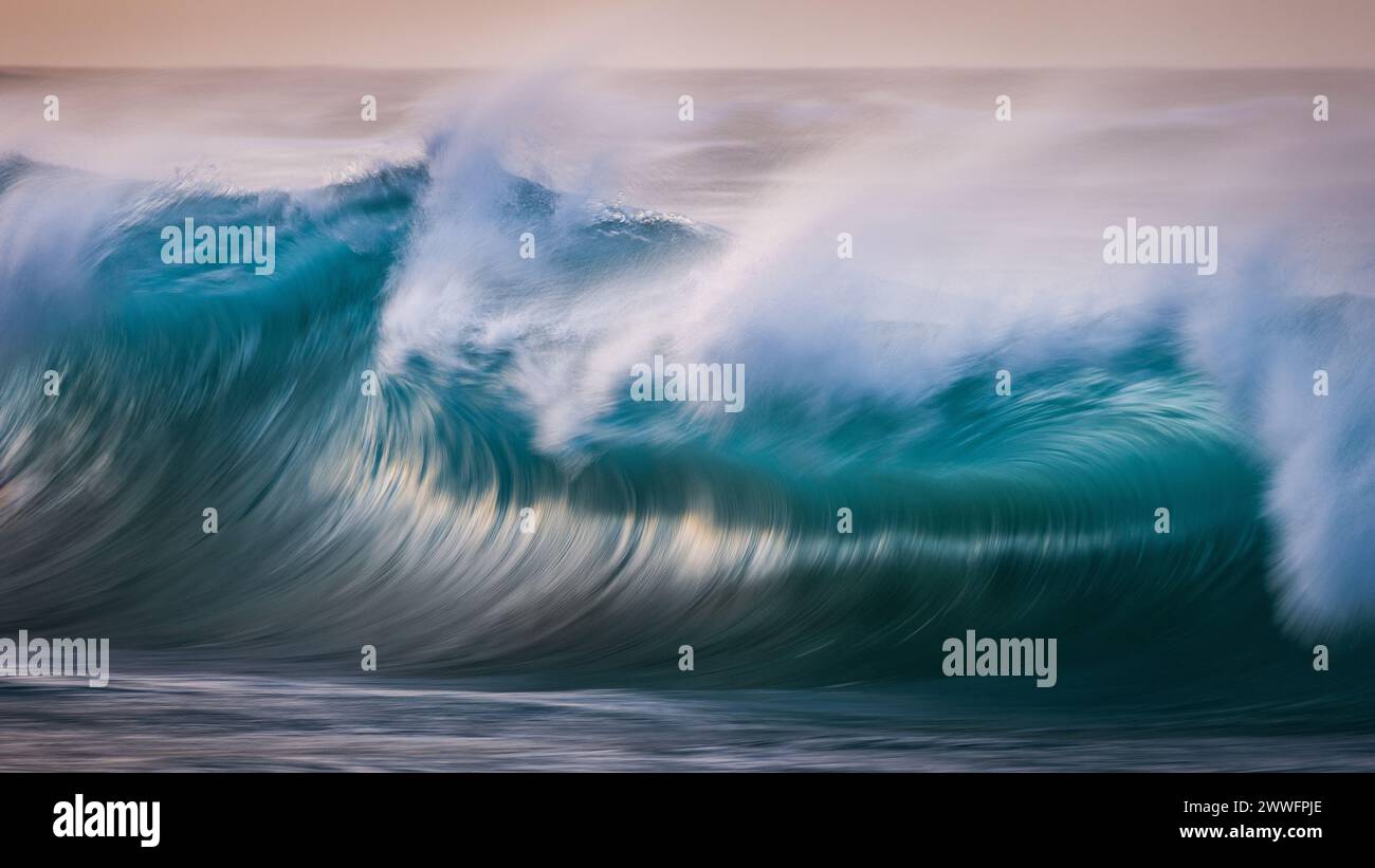 Un lento colpo di panning dell'otturatore di un'onda al Sandy Beach Park alla luce del mattino presto. Foto Stock