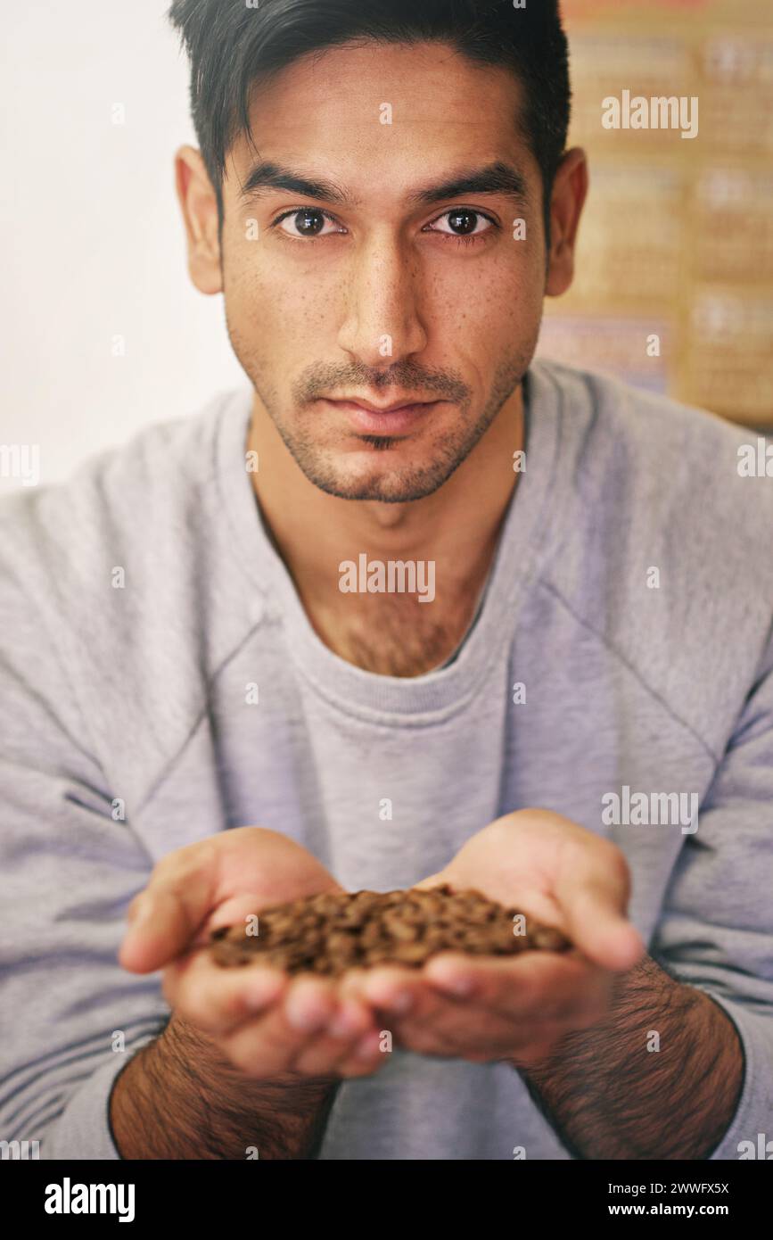 Uomo, che tiene in mano cereali di caffè e produce con orgoglio chicchi biologici di qualità superiore in magazzino. Persona, dipendente e produzione per esportazione, industria Foto Stock
