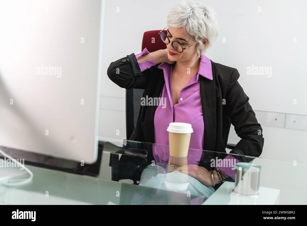 Donna d'affari anziana che allevia la tensione al collo - affaticamento sul lavoro, gestione dello stress in ufficio - comfort pausa in orari di lavoro affollati, prova a gestire la pressione. Foto Stock