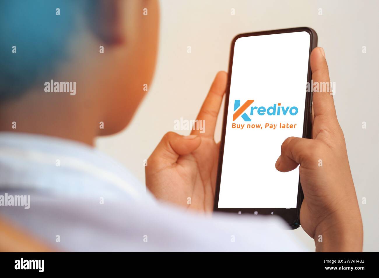 Adolescenti in possesso di cellulari che visualizzano l'applicazione Kredivo su smartphone, un metodo di pagamento popolare in Indonesia Foto Stock