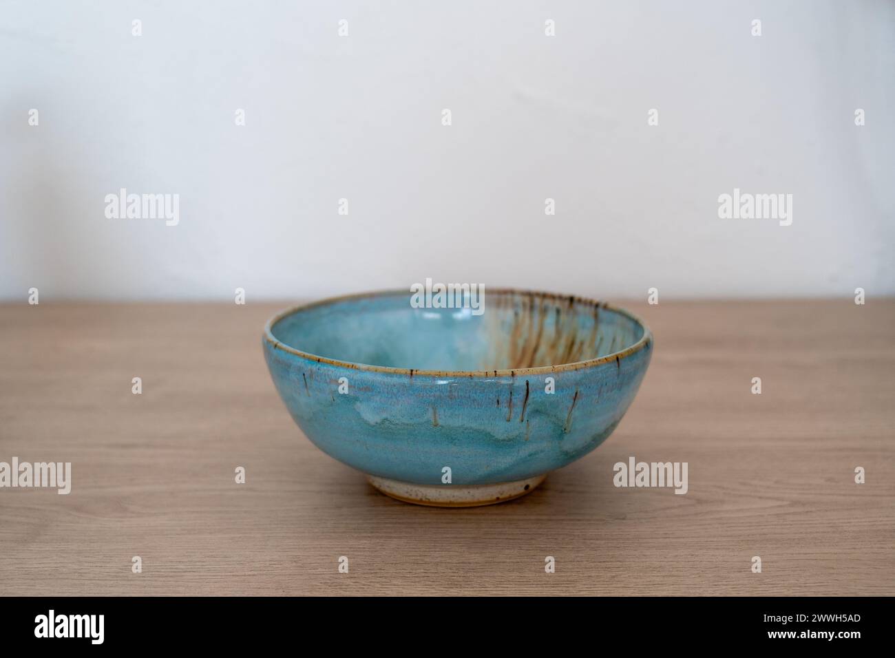 Ciotola in ceramica blu smaltata fatta a mano su un bancone in legno. Foto di alta qualità Foto Stock