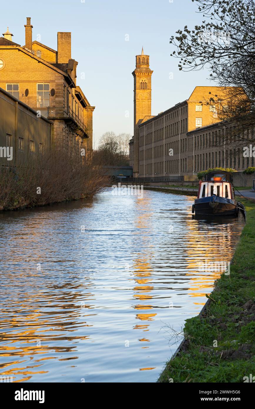 La torre italianata di New Mill, Saltaire, si riflette nelle acque del canale Leeds-Liverpool, vicino a Bradford, West Yorkshire Foto Stock