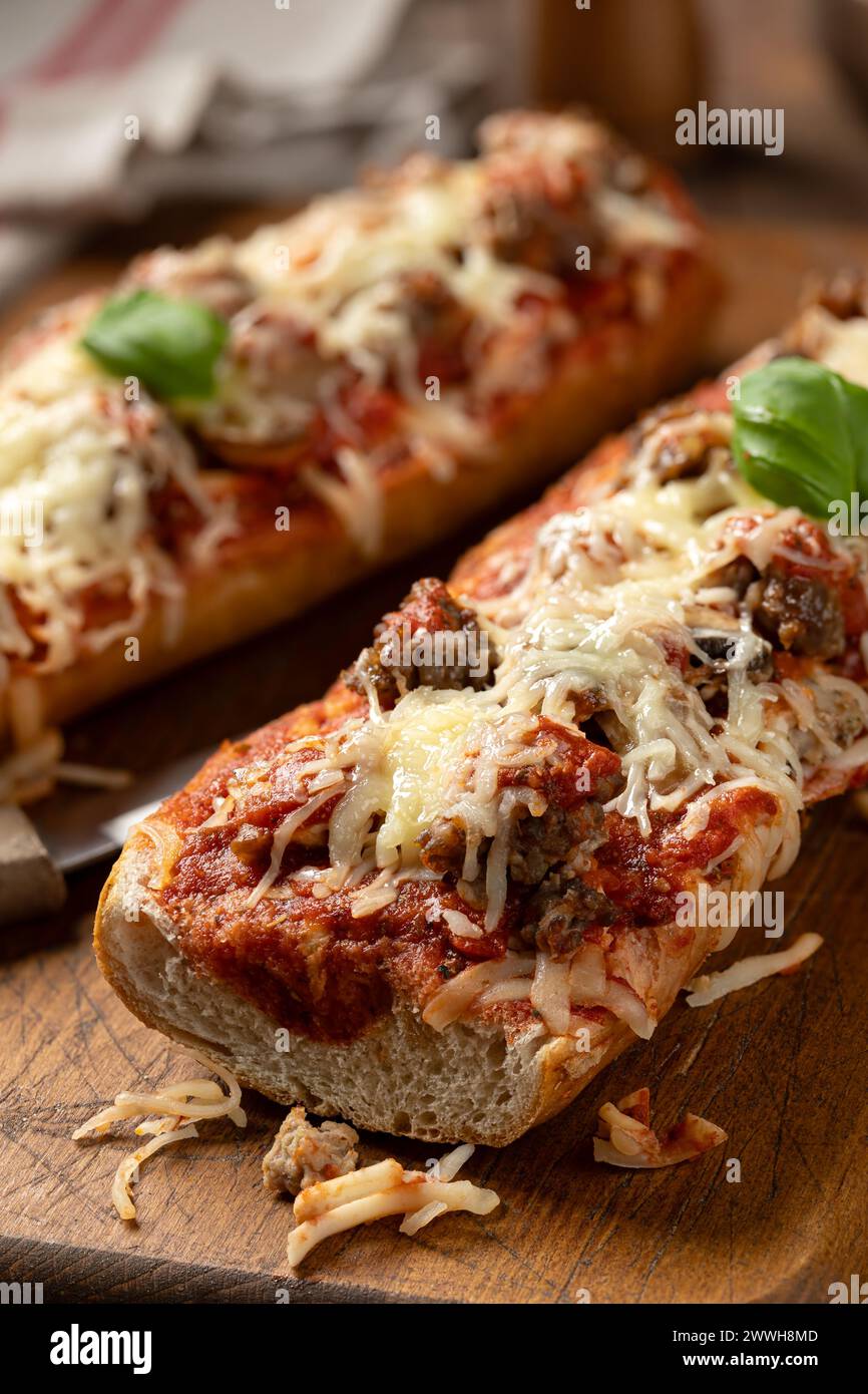 Pizza con pane fatto con salsiccia, mozzarella e pomodoro su un vecchio tagliere di legno Foto Stock