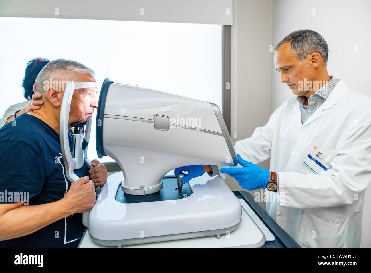 Uomo anziano durante un'ispezione di glaucoma con uno scanner sull'allievo in una clinica Foto Stock