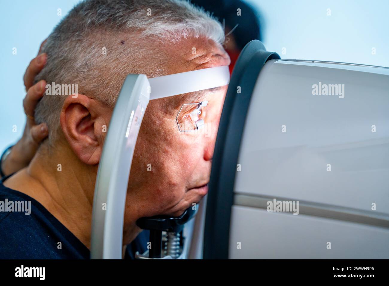 Vista laterale primo piano di un anziano che appoggia la testa sullo scanner per controllare il glaucoma Foto Stock