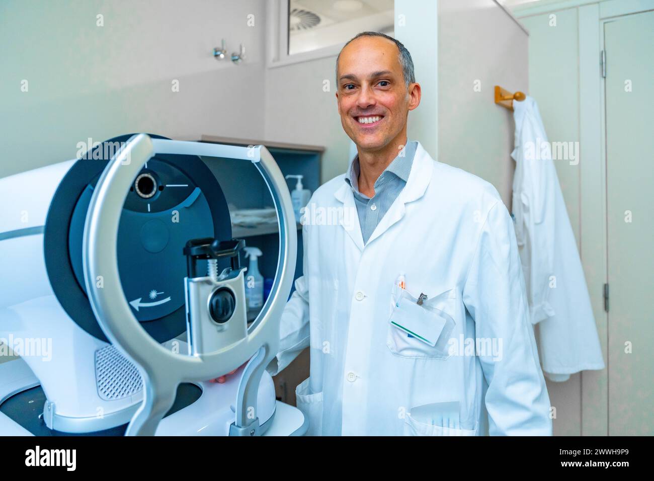 Ritratto di un oftalmologo in una clinica innovativa in piedi accanto a una macchina laser per il trattamento del glaucoma Foto Stock