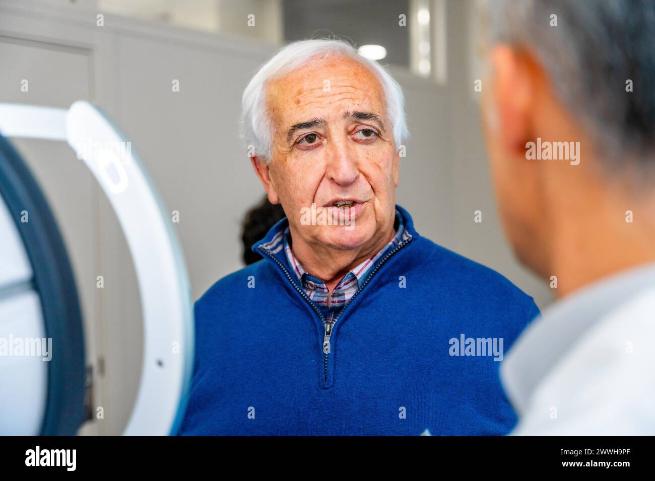 Un uomo anziano soddisfatto che parla con un oftalmologo in clinica dopo aver ricevuto un trattamento glaucoma innovativo con laser Foto Stock