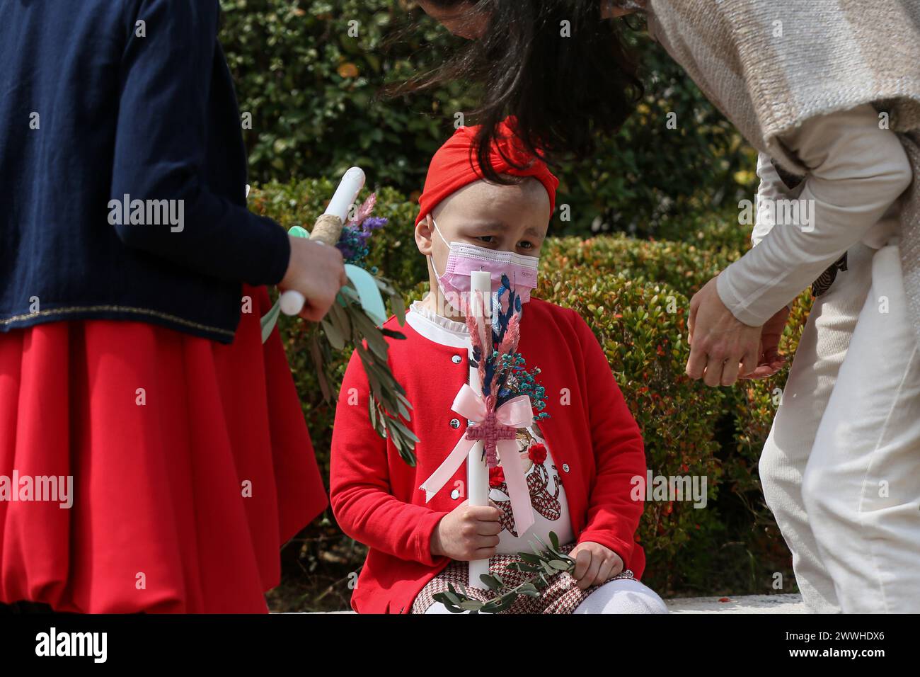 Camille, una paziente libanese di 5 anni che soffre di cancro, tiene una candela mentre partecipa alla messa della domenica delle Palme nella chiesa di Bkerki, a nord di Beirut Foto Stock
