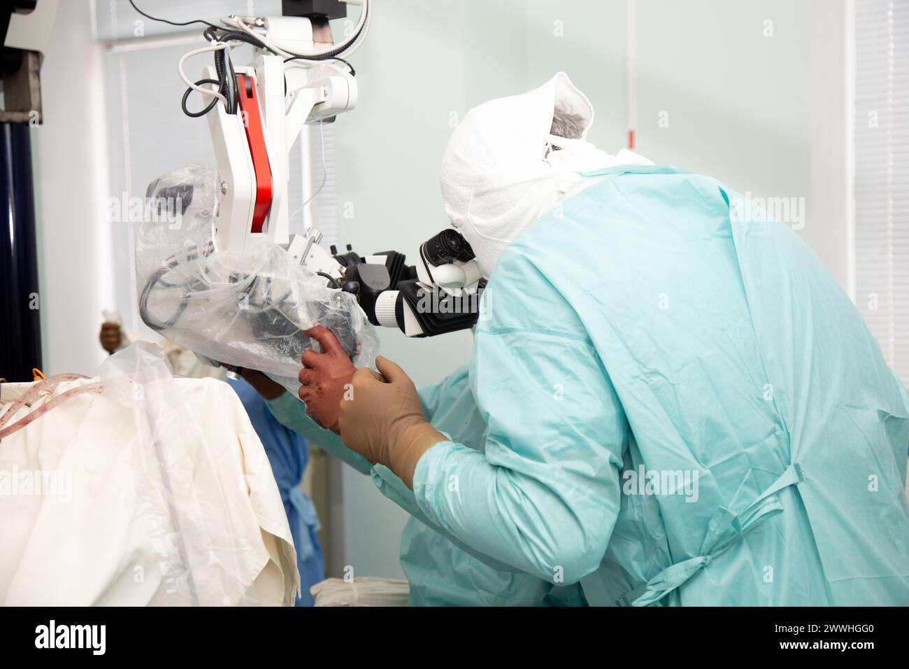 Un medico neurochirurgo esamina un microscopio durante un'operazione. Neurochirurgia e microchirurgia. Foto Stock