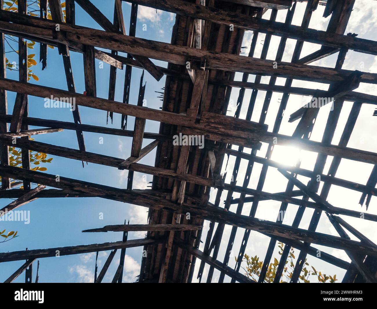 Vista dal basso del tetto di un vecchio edificio con strutture in legno contro il cielo. Tetto in legno distrutto nell'edificio abbandonato. Foto Stock