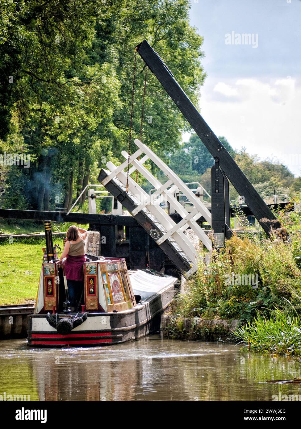 Storico motoscafo che attraversa un ponte di risalita e si trova in una stretta chiusa sul canale di Northampton, Inghilterra, Regno Unito, Regno Unito, Northamptonshire Foto Stock