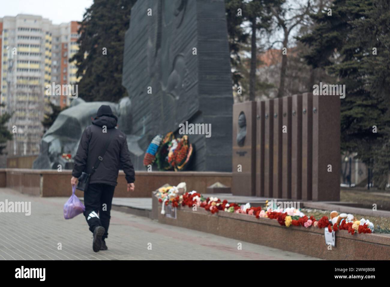 Un passante passeggia davanti a un monumento vicino al Monumento della Gloria a Voronezh in memoria delle vittime dei terroristi nel municipio di Crocus. Il 24 marzo, il governo russo ha dichiarato lutto. In memoria delle vittime dell'attentato terroristico al municipio di Crocus a Voronezh, gli eventi di intrattenimento sono stati cancellati. Le bandiere degli edifici governativi sono a metà del personale. Le candele in lutto sono posizionate sui cartelloni della città. Le persone trasportano fiori e giocattoli per bambini in luoghi memoriali spontanei. (Foto di Mihail Siergiejevicz/SOPA Images/Sipa USA) Foto Stock