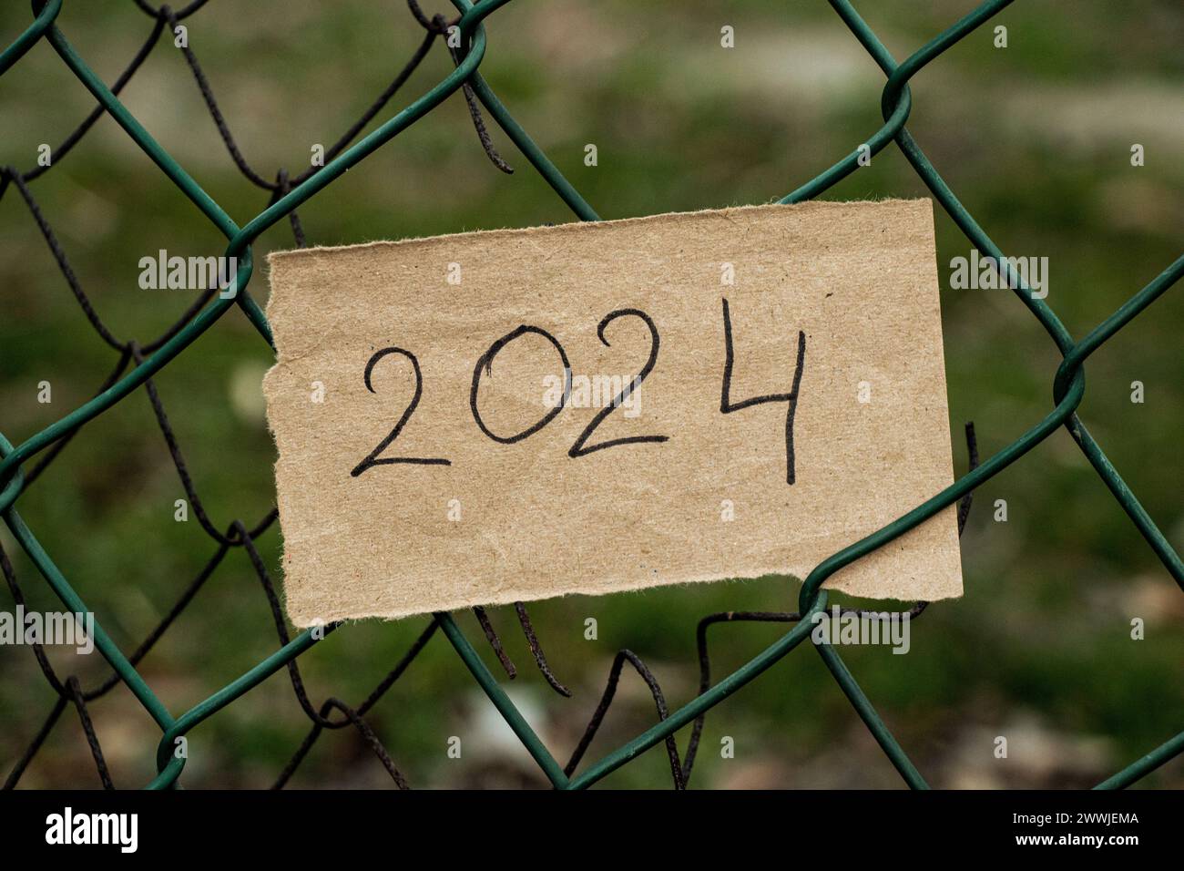 Un pezzo di carta marrone con il testo 2024 è appeso sulla recinzione come sfondo, l'anno 2024 Foto Stock