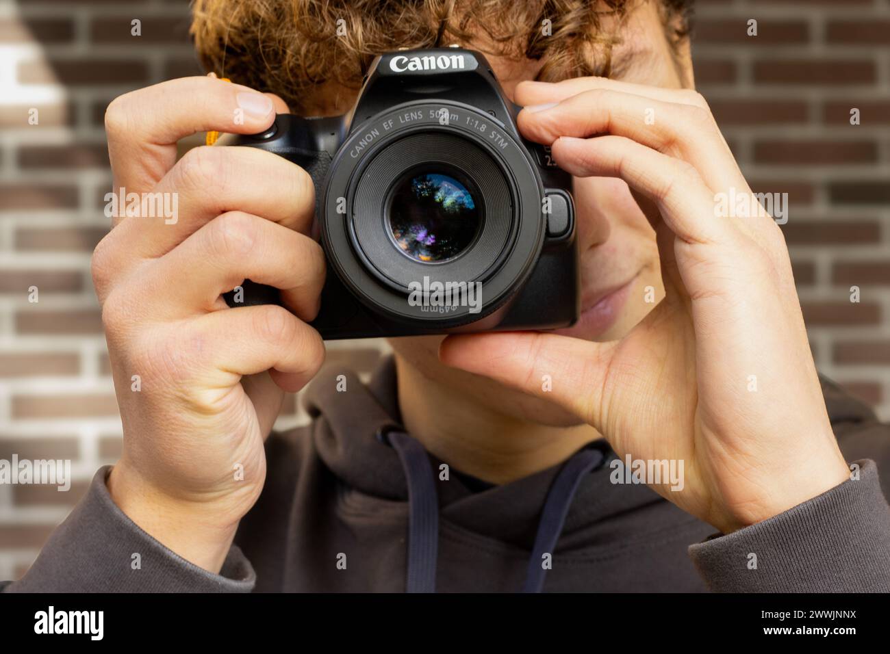 Ragazzo che scatta una foto con una fotocamera DSLR Foto Stock