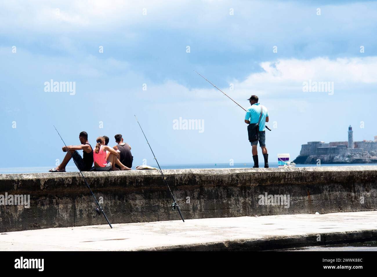 Le persone si rilassano e pescano sulle pareti del mare di fronte al forte di El Malecon a l'Avana, Cuba. Foto Stock