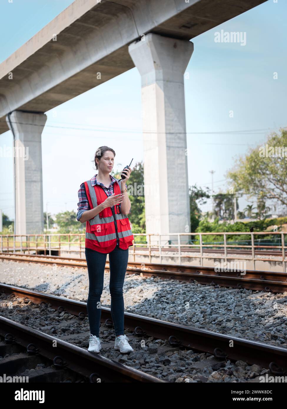 Una donna ingegnere ferroviario utilizza un walkie-talkie che parla con il reparto di manutenzione durante i lavori in cantiere del garage ferroviario. Foto Stock