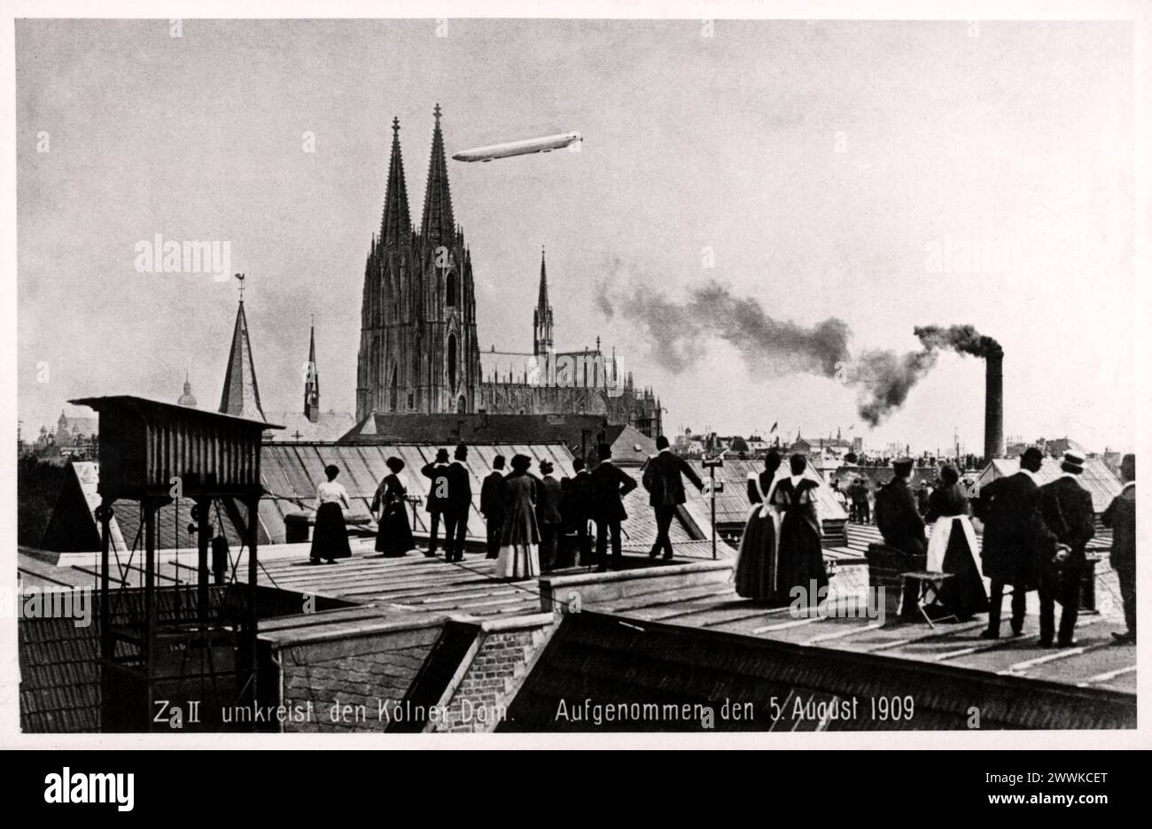 1909 , 5 agosto , COLONIA , GERMANIA : il GRAF ZEPPELIN II sorvola Colonia . Il primo viaggio intorno alla Cattedrale di Colonia (il Kolner Dom), con persone che si arrampicano sui tetti delle case che osservano l'evento storico. Foto di un fotografo sconosciuto . - GERMANIA - DUOMO CATTEDRALE DI COLONIA - VOLO - FLY - POSTA AEREA - POSTA AEREA - VIAGGIO - GERMANIA - FOTO STORICHE - FOTO STORICHE - CASA - HOME - ABITAZIONE - ARCHITETTURA - ARCHITETTURA - GEOGRAFIA - GEOGRAFIA - GIARDINO - GIARDINO - DIRIGIBILE - VOLO - FLY - quartiere - città - tetti - tetti - CATTEDRALE - CHIESA - CHIESA - RICORDI - MEMORIA Foto Stock