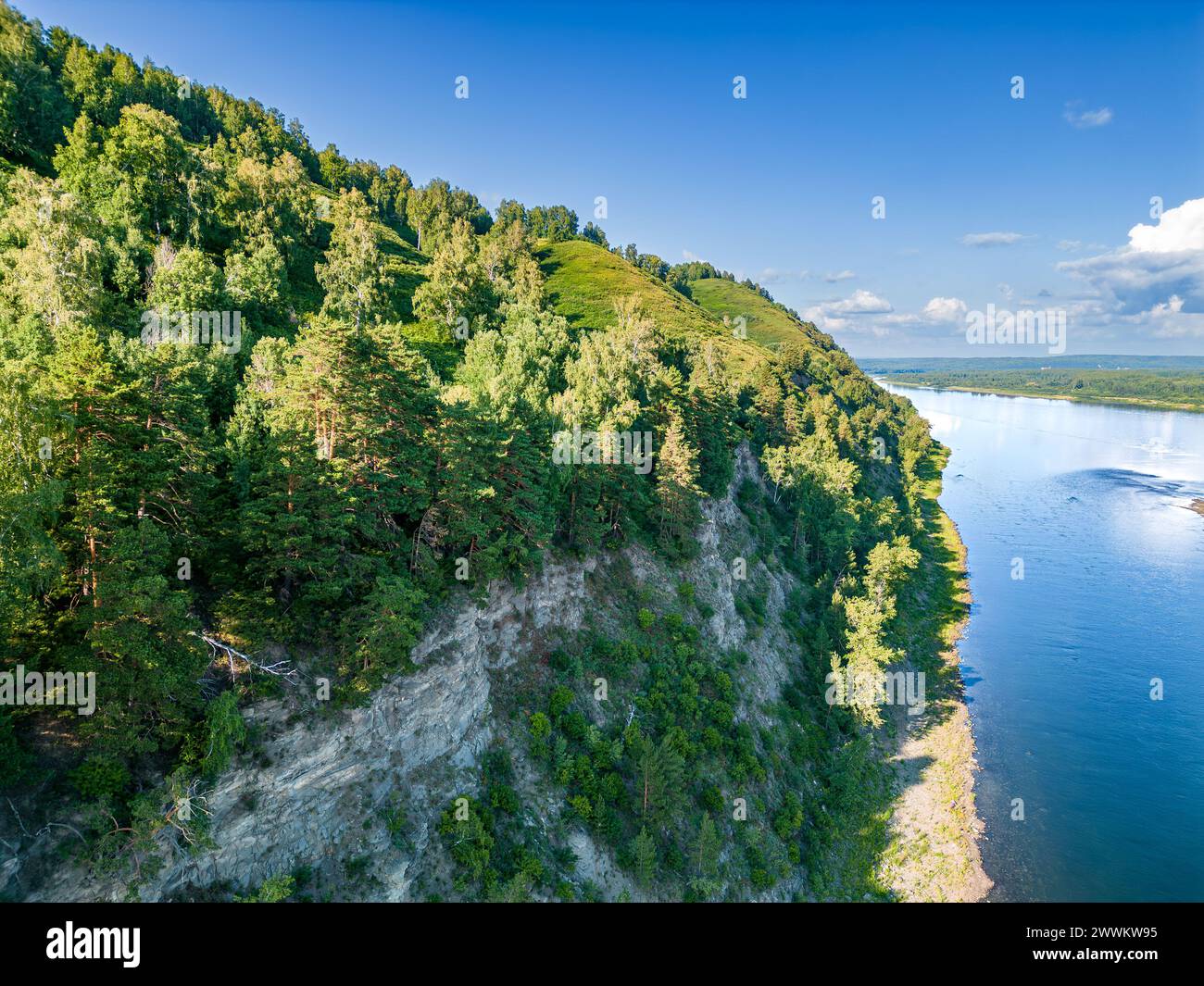 La roccia, su cui crescono foreste miste e arbusti, forma la riva di un tranquillo fiume di pianura. Dal punto di vista di un uccello Foto Stock