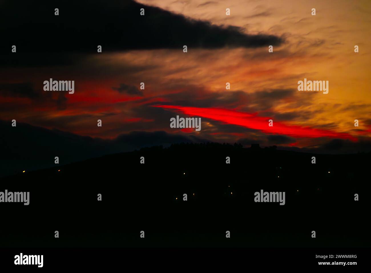 Nel tranquillo crepuscolo, un tramonto rosso inonda il cielo di sfumature ardenti, creando uno spettacolo suggestivo e celeste all'orizzonte. Foto Stock